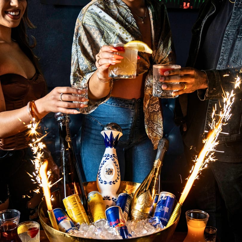Three people holding cocktails, with a bucket of drinks and sparklers at Chako's Social.